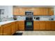 Galley kitchen features wood cabinets, light countertops, and black appliances at 14938 W Mauna Loa Ln, Surprise, AZ 85379