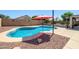 Backyard pool with a red umbrella and desert landscaping at 14938 W Mauna Loa Ln, Surprise, AZ 85379