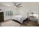 Cozy bedroom with plush carpeting, white walls, a ceiling fan, a large window and comfortable furnishings at 16526 W Desert Ln, Surprise, AZ 85388