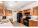 Functional kitchen with wood cabinetry, black appliances, and a tiled floor at 17585 N Coyote Lakes Pkwy, Surprise, AZ 85378