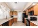 Functional kitchen featuring wooden cabinets, black appliances, and tiled floors at 17585 N Coyote Lakes Pkwy, Surprise, AZ 85378