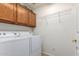 Functional laundry room equipped with modern washer, dryer, and overhead storage at 17585 N Coyote Lakes Pkwy, Surprise, AZ 85378