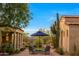 Charming outdoor patio with desert landscaping, a blue umbrella, and elegant seating under a clear blue sky at 19054 N 97Th Pl, Scottsdale, AZ 85255