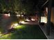 Backyard featuring lush landscaping, decorative lighting, and a covered patio area for serene evenings at 21013 W Wycliff Dr, Buckeye, AZ 85396