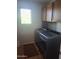 Laundry room featuring modern washer and dryer units, storage cabinets and a window at 21013 W Wycliff Dr, Buckeye, AZ 85396