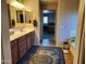 En suite bathroom with dual sinks, wood cabinets, large mirror, and stylish bath mat at 21013 W Wycliff Dr, Buckeye, AZ 85396