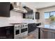Elegant kitchen boasts stainless steel range hood, appliances, and dark cabinets with white backsplash at 31409 N 58Th Pl, Cave Creek, AZ 85331