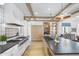Bright kitchen with black countertops, island sink, wood beam ceiling, and stainless steel stove at 325 W Solano Dr, Phoenix, AZ 85013
