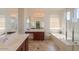 Bright bathroom featuring dual sinks, soaking tub, walk-in shower, and tile flooring at 43561 W Snow Dr, Maricopa, AZ 85138
