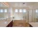 Bright bathroom featuring double sinks, a soaking tub, and a glass-enclosed shower at 43561 W Snow Dr, Maricopa, AZ 85138