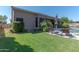 A spacious backyard with a lush green lawn, a private pool, a covered patio, and mature trees and landscaping at 4410 E Robin Ln, Phoenix, AZ 85050