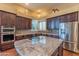 A kitchen features rich wood cabinets, granite countertops, stainless steel appliances, and a center island with a glass cooktop at 4410 E Robin Ln, Phoenix, AZ 85050