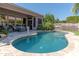 A backyard featuring a lagoon-style pool surrounded by grass and palm trees, and a covered patio with outdoor seating at 4410 E Robin Ln, Phoenix, AZ 85050