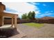 Serene backyard with gravel landscape, small lawn area, and a covered patio for outdoor relaxation at 44865 W Woody Rd, Maricopa, AZ 85139