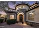 Arched stone entryway and door of a tan home at twilight with well manicured landscaping at 5434 E Barwick Dr, Cave Creek, AZ 85331