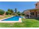 Inviting backyard pool with inflatable toys, green lawn, covered patio with dining area, and lush landscaping at 6446 E Beverly Ln, Scottsdale, AZ 85254