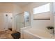 Primary bath features a soaking tub, walk-in shower with glass door, and light-filled window at 6931 S Four Peaks Way, Chandler, AZ 85249