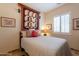 Cozy bedroom with tiled floors, neutral walls, shuttered window, and unique textile wall decor at 6931 S Four Peaks Way, Chandler, AZ 85249