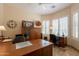 Home office with tiled floors, large windows with shutters, ceiling fan, and ample desk and workspace at 6931 S Four Peaks Way, Chandler, AZ 85249
