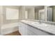 Bright bathroom featuring a double sink vanity with granite countertop and a tub under a window at 822 E Agua Fria Ln, Avondale, AZ 85323