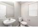 Cozy half bathroom showcasing a pedestal sink, toilet, neutral wall color, and a window for natural light at 822 E Agua Fria Ln, Avondale, AZ 85323