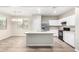 Bright kitchen featuring an island with a sink, stainless steel refrigerator, and wood-style flooring at 822 E Agua Fria Ln, Avondale, AZ 85323