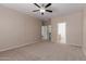 A spacious main bedroom featuring neutral walls, plush carpeting, ceiling fan, and en suite bathroom and walk-in closet at 10009 W Raymond St, Tolleson, AZ 85353