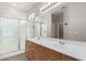 Bathroom featuring double sink vanity, stone countertops, wood cabinets, glass enclosed shower, and modern fixtures at 10735 E Kilarea Ave, Mesa, AZ 85209