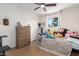 Bright bedroom featuring a ceiling fan, wood floors, a window, and a wooden dresser at 12043 N 46Th Ave, Glendale, AZ 85304
