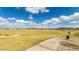 A lush, green community park features a walking trail, open green space, and mature trees under a bright sky at 14323 W Alameda Rd, Surprise, AZ 85387