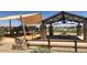 A shady community playground featuring stone columns, a sun shade, picnic tables, and benches at 14323 W Alameda Rd, Surprise, AZ 85387
