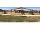 A bright and cheerful community playground features a sun shade, wood chips, mature landscaping, and seating at 14323 W Alameda Rd, Surprise, AZ 85387