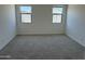 Empty bedroom with neutral carpeting, two windows, and neutral colored walls at 18240 W La Senda Dr, Surprise, AZ 85387