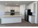 Modern kitchen features stainless steel appliances, white cabinets, and a center island with a sink at 18240 W La Senda Dr, Surprise, AZ 85387