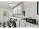 Well-lit laundry room boasts modern washer and dryer, overhead cabinets, marble counters, and black and white tile floor at 4243 E Avalon Dr, Phoenix, AZ 85018