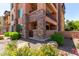 Close-up of condo's stone exterior, framed by beautiful landscaping with flowers and greenery at 4803 N Woodmere Fairway -- # 1002, Scottsdale, AZ 85251