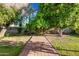 Lush backyard featuring mature trees, green lawns, and a brick pathway, creating a serene outdoor oasis at 5803 W John Cabot Rd, Glendale, AZ 85308