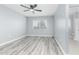 Bedroom with light gray walls, a ceiling fan, modern laminate flooring, and a window at 10022 W Mountain View Rd, Sun City, AZ 85351