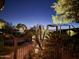 Beautiful backyard with mature landscaping, wrought iron fencing, and outdoor lighting at 11320 E Winchcomb Dr, Scottsdale, AZ 85255