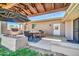 Inviting covered patio with outdoor dining area, stone fireplace, grill, and manicured landscaping at 1208 E Tuckey Ln, Phoenix, AZ 85014