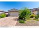 Single-story home with a two-car garage and brick paver driveway, surrounded by landscaped desert plants and blue skies at 12204 W Parkway Ln, Avondale, AZ 85323