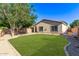 Large backyard showcasing a green lawn, mature trees, gravel landscaping, and home exterior at 14864 W Riviera Dr, Surprise, AZ 85379