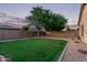 Large backyard featuring a green lawn, mature trees, rock landscaping, and brick perimeter wall at 14864 W Riviera Dr, Surprise, AZ 85379
