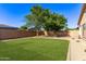 Lush green lawn complemented by decorative rock landscaping, mature trees, and a perimeter wall for privacy at 14864 W Riviera Dr, Surprise, AZ 85379
