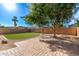 Spacious backyard with a lush lawn, brick patio, mature trees, and stone landscaping at 14864 W Riviera Dr, Surprise, AZ 85379