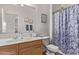 Cozy bathroom featuring a wood vanity, a floral shower curtain, and a framed wall mirror at 14864 W Riviera Dr, Surprise, AZ 85379