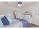 Bright bedroom with a decorative light fixture, white walls, and a glimpse into the ensuite bathroom at 14864 W Riviera Dr, Surprise, AZ 85379