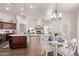 Bright dining room with modern chandelier, leading to the kitchen, fireplace and living room at 14864 W Riviera Dr, Surprise, AZ 85379