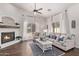 Bright living room featuring a fireplace, ceiling fan, modern furniture, and natural light from the large windows at 14864 W Riviera Dr, Surprise, AZ 85379