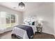 The bright main bedroom features a modern light fixture, a large window, and neutral walls at 14864 W Riviera Dr, Surprise, AZ 85379